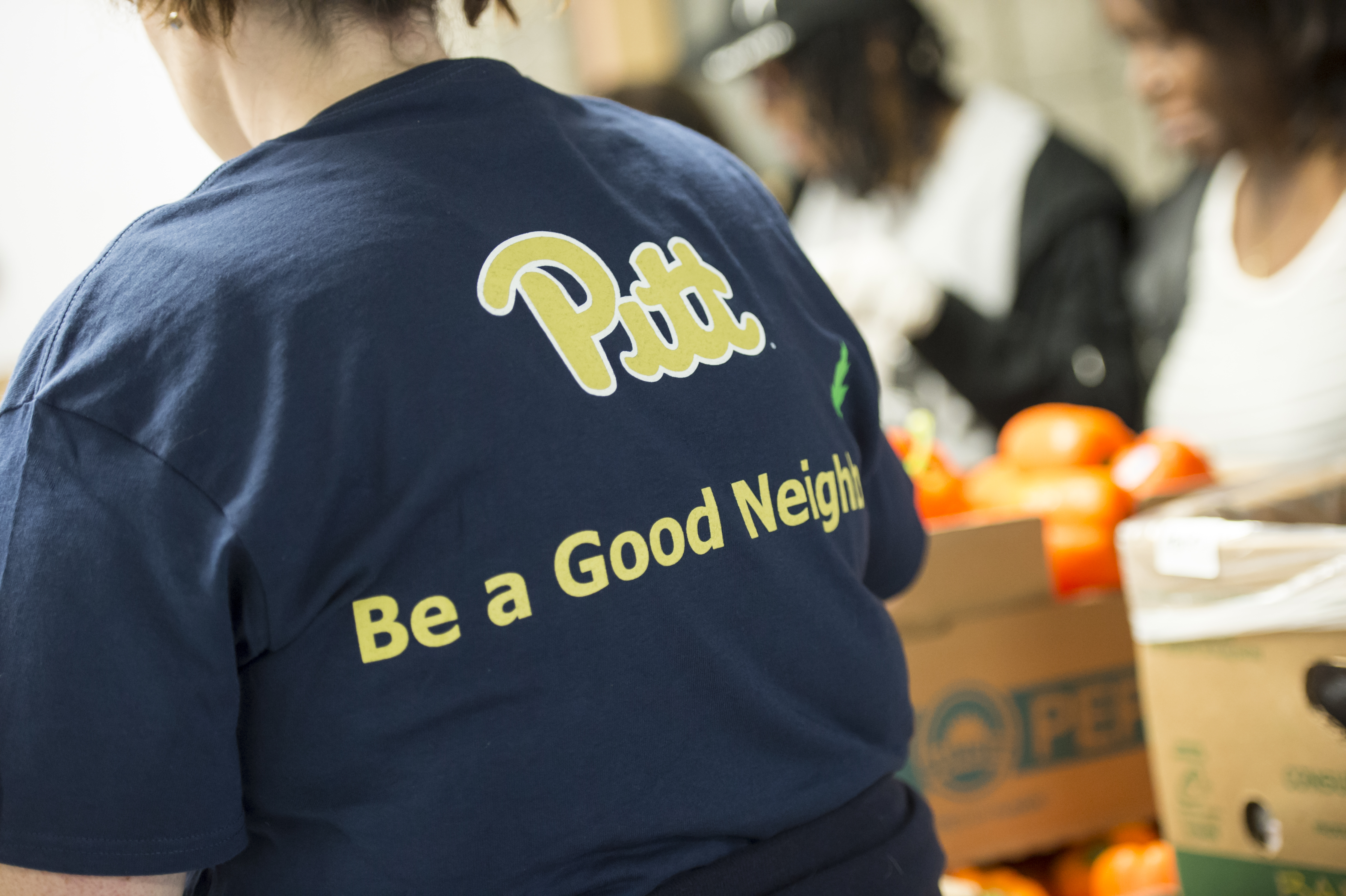 Back of a person wearing a blue t-shirt that says "Pitt Be a Good Neighbor"